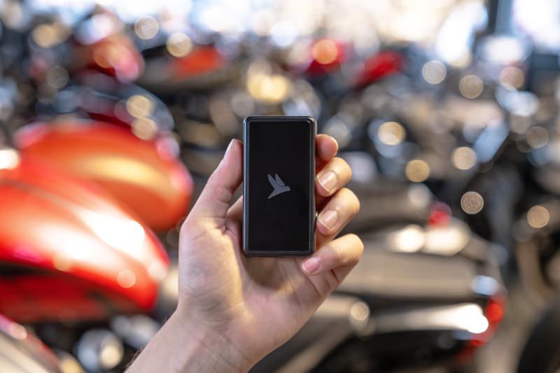 Main tenant un traceur GPS Flashbird dans un showroom moto
